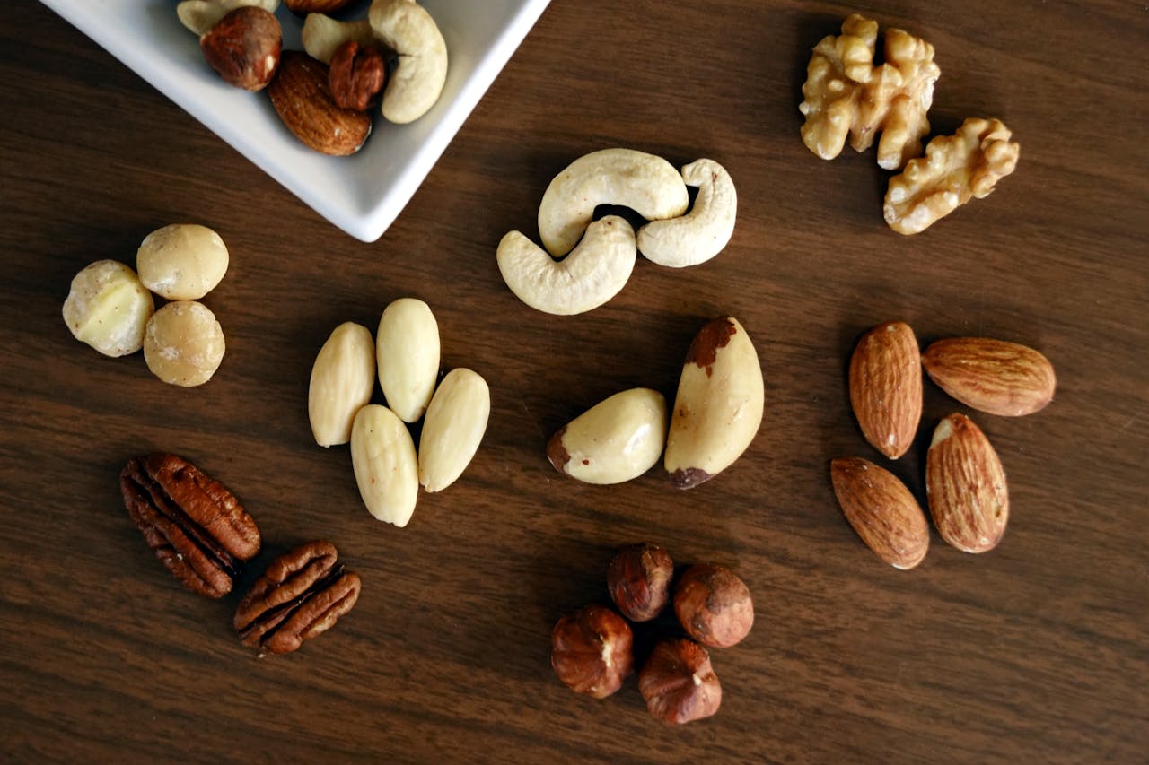 Close-up of various nuts on a wooden table, showcasing healthy snacking options.
